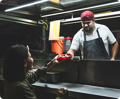 A food truck vendor handing food to a customer.